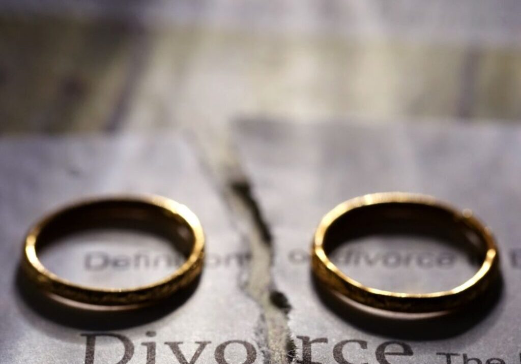 Rings laying on divorce paper that is torn in half.